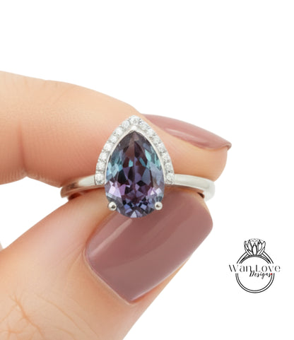 A close-up of a hand holding a ring with a large, colorful gemstone, likely a diamond, on the finger.