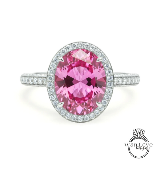 A pink gemstone ring with a halo of diamonds around the center stone.