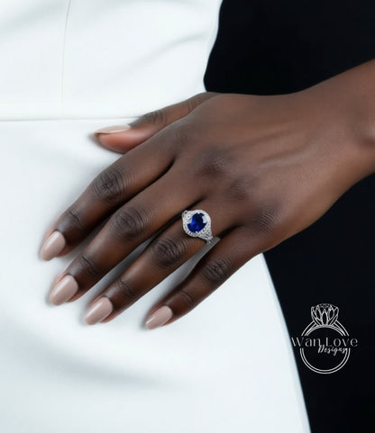 A close-up of a hand wearing a ring with a large blue gemstone, resting on a white surface.