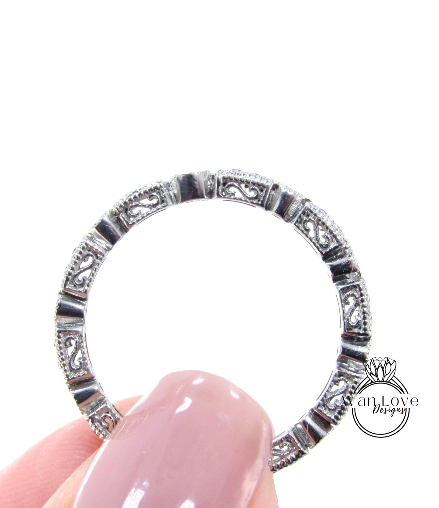 A close-up view of a person's hand holding a ring with intricate designs.