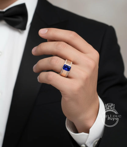 A close-up of a person's hand wearing a gold ring with a blue gemstone, wearing a black tuxedo.