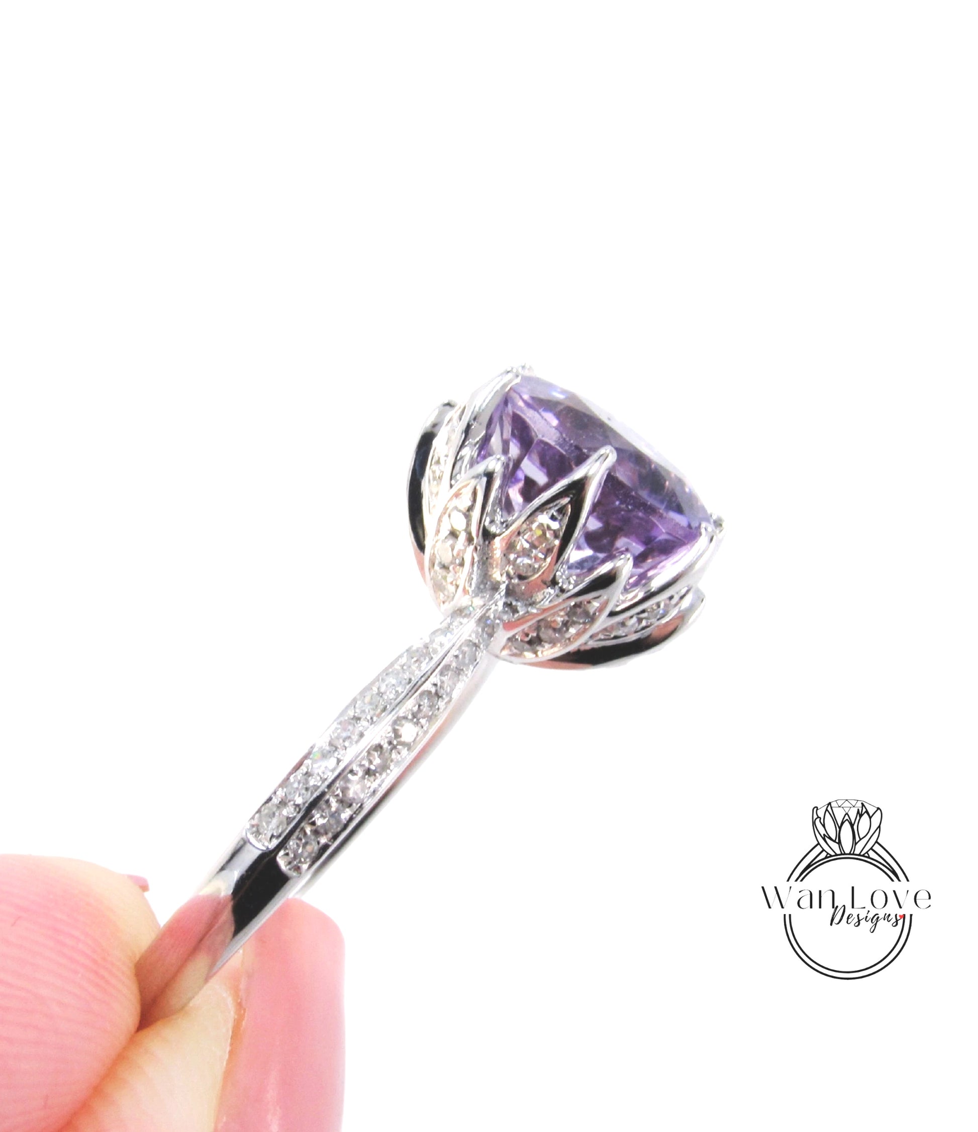 A close-up image of a person's hand holding a silver ring with a large, purple gemstone, likely an amethyst, on the ring.