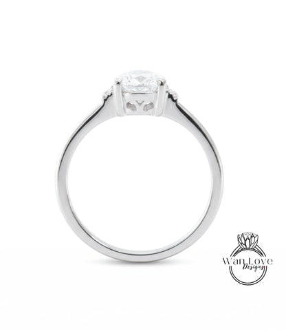 A silver engagement ring with a large central diamond and a smaller diamond on either side.
