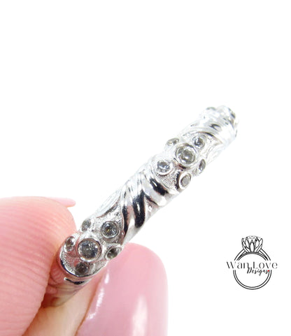 A close-up image of a person's hand holding a silver ring adorned with small, round stones.