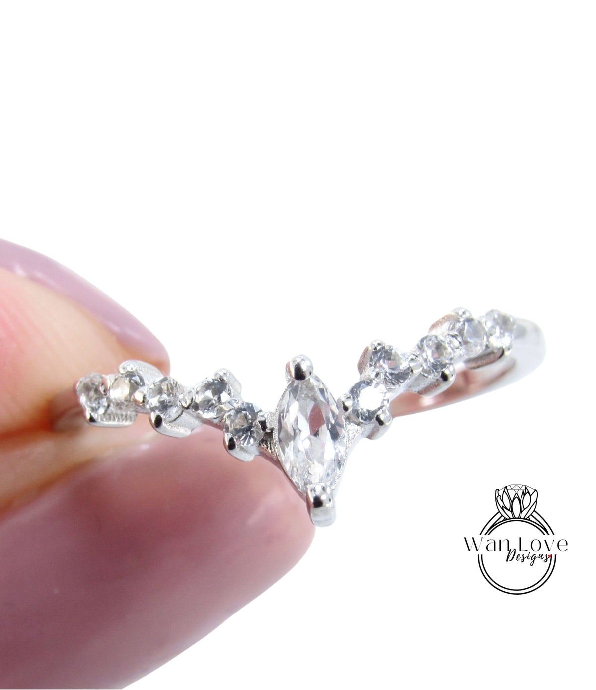 A close-up image of a person's hand holding a silver ring with a large central diamond surrounded by smaller diamonds.