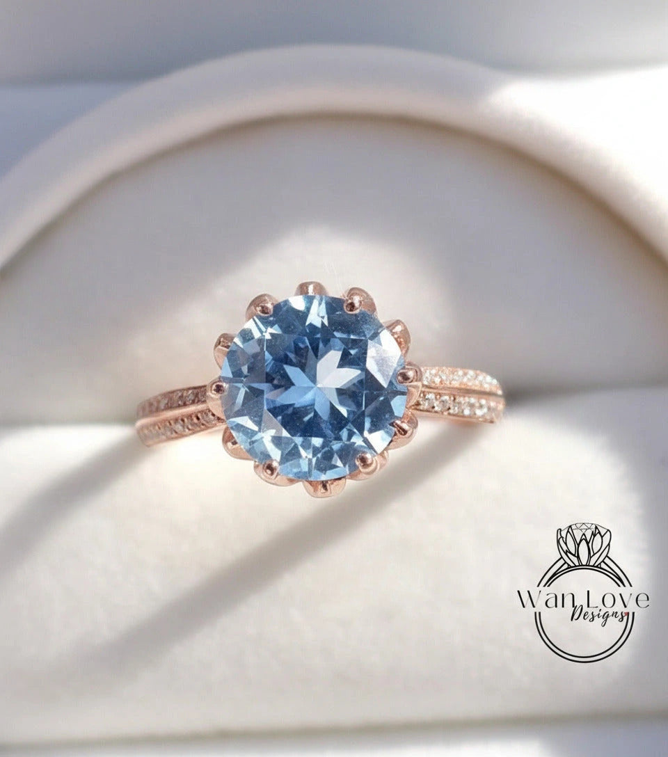 A close-up image of a rose gold ring with a large blue gemstone, placed on a white background.