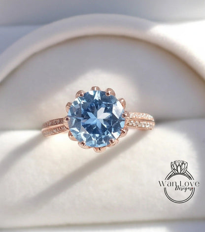 A close-up image of a rose gold ring with a large blue gemstone, placed on a white background.