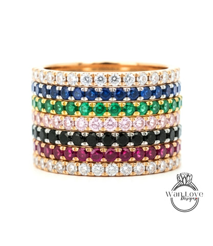 A stack of colorful gemstone rings with various colored stones set in a gold band.