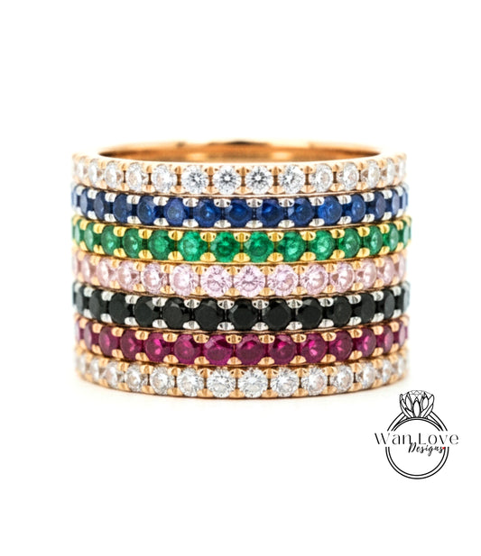 A stack of colorful gemstone rings with various colored stones set in a gold band.