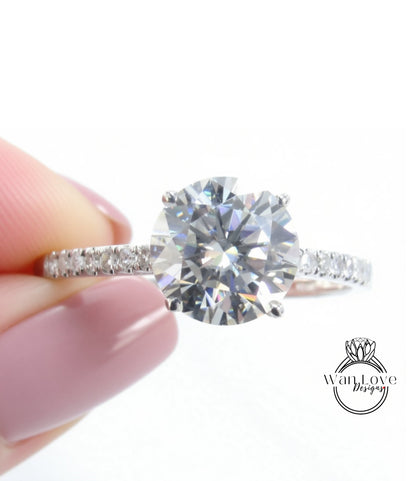 A close-up image of a person's hand holding a diamond engagement ring with a large, brilliant-cut diamond set in a silver band.
