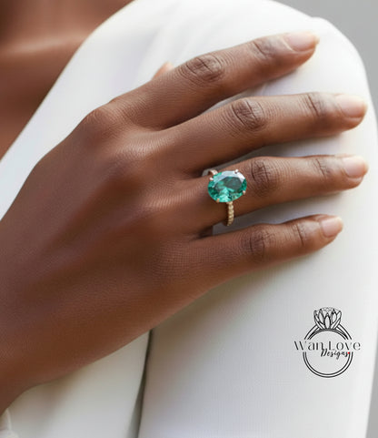 A close-up of a person's hand wearing a large, green gemstone ring on the ring finger.