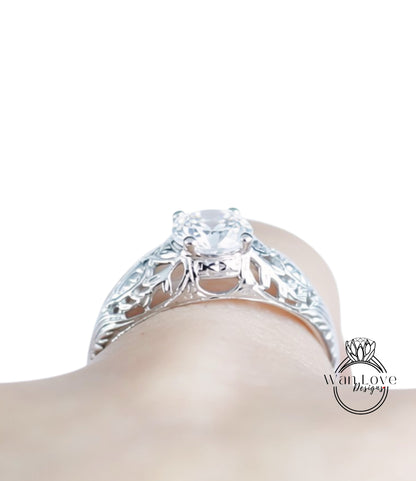 A close-up view of a silver engagement ring with a large central diamond and intricate floral designs around the band.