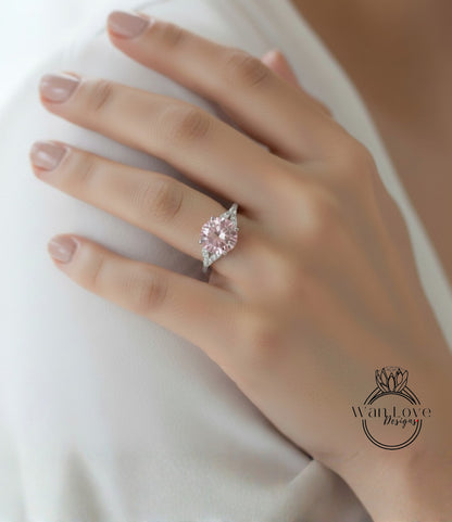 A close-up of a person's hand wearing a pink diamond engagement ring.