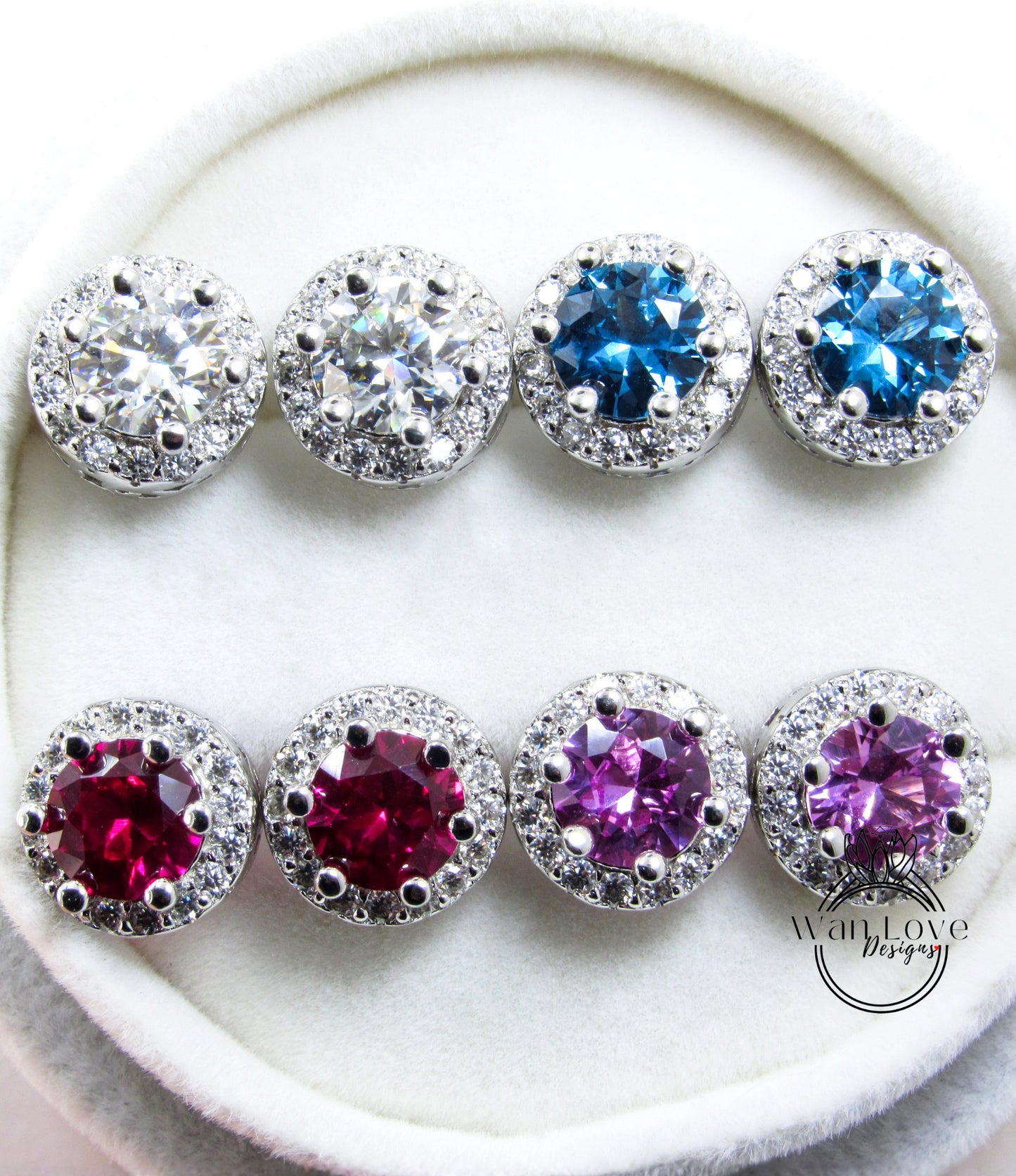 A pair of earrings with various colored gemstones, including clear, blue, red, and purple stones, set in a silver and white design.