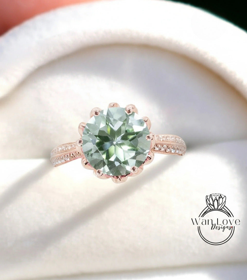 A large, round, green gemstone ring with a scalloped edge and a rose gold band, displayed on a white fabric background.