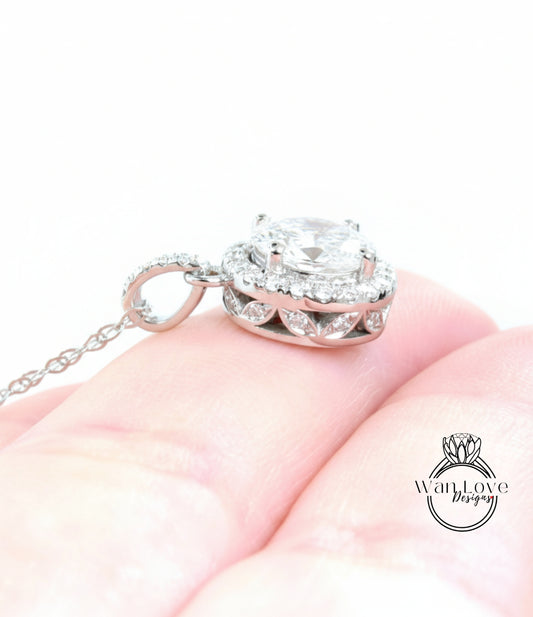 A close-up image of a person's hand holding a delicate silver necklace with a large, sparkling diamond pendant.