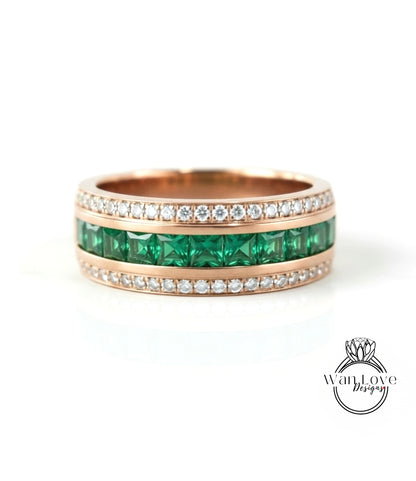A gold ring with a row of green gemstones, including diamonds, set in a band.