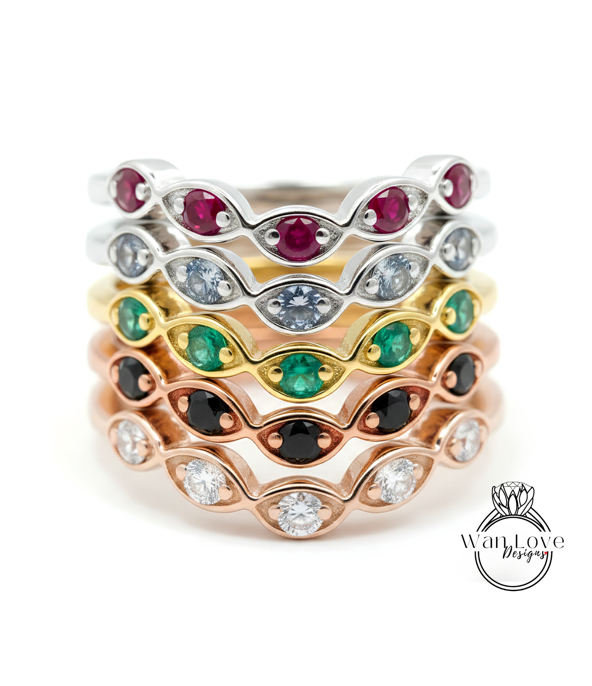 A stack of rings with various colored gemstones, including red, green, and white stones, set in a rose gold band.