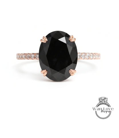 A large oval-shaped black diamond ring with a thin gold band and small diamonds around the band.