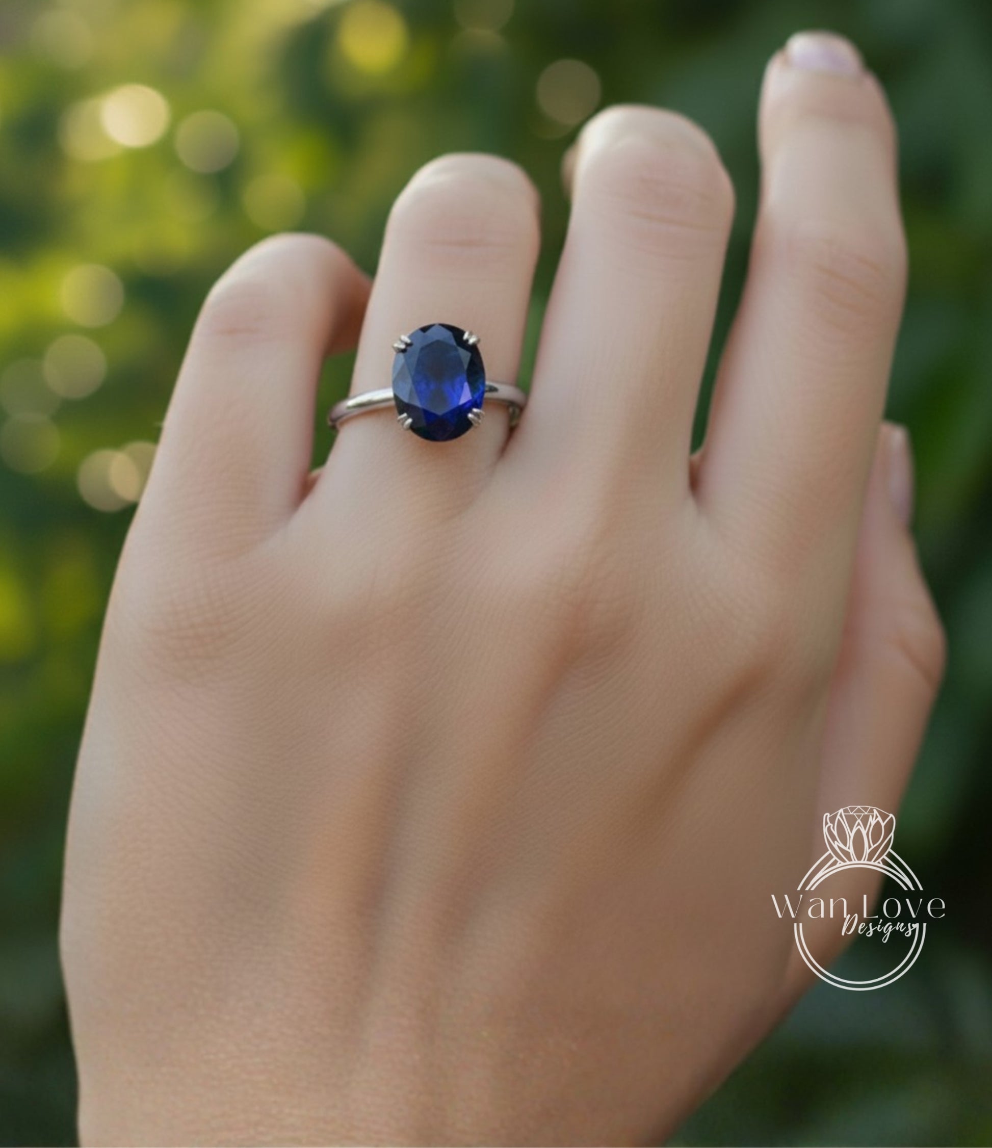 A close-up of a hand wearing a ring with a large blue gemstone, likely a sapphire, on the ring finger.