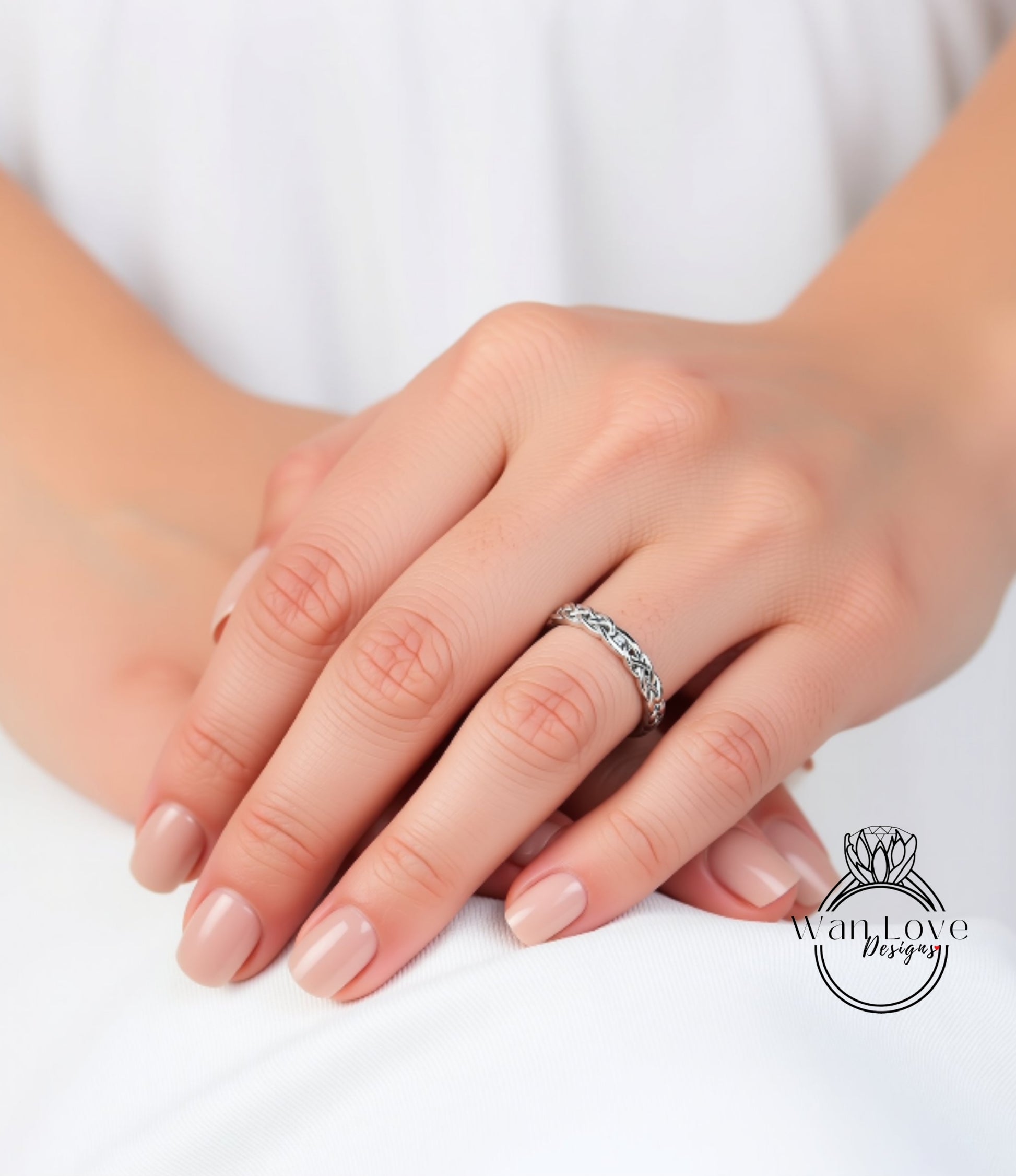 A close-up image of a person's hands wearing a silver ring on the ring finger.