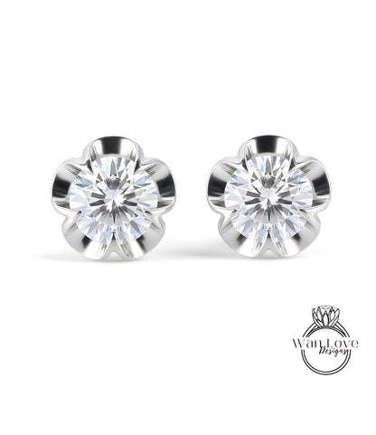 A pair of elegant earrings with a large, brilliant-cut diamond set in a silver flower-shaped design.