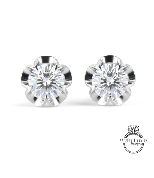 A pair of elegant earrings with a large, brilliant-cut diamond set in a silver flower-shaped design.