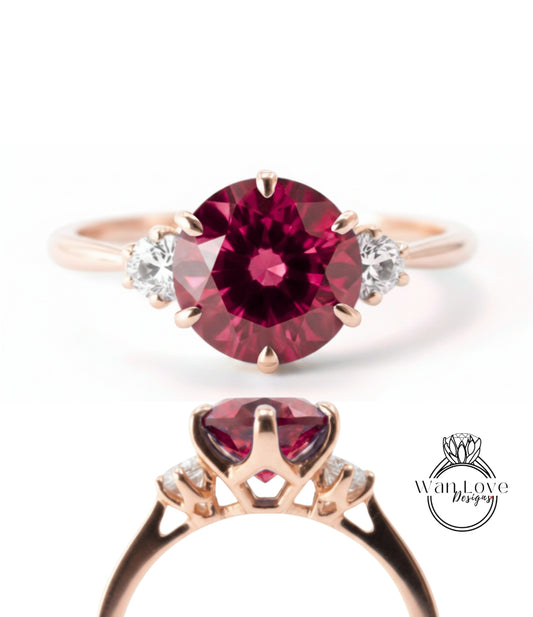 a beautiful engagement ring with a large, deep red gemstone set in a rose gold band. The ring is adorned with three smaller diamonds on either side of the large gemstone, adding to its elegance and sophistication.