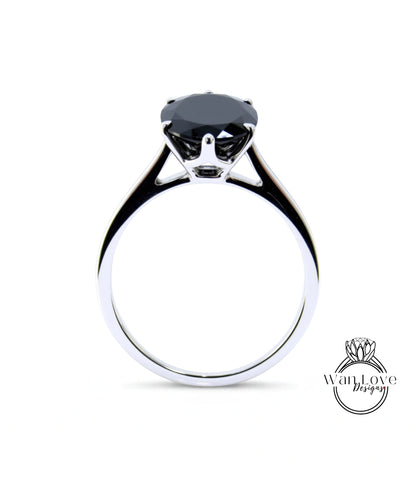 A silver ring with a large black gemstone, likely a diamond, set in the center.