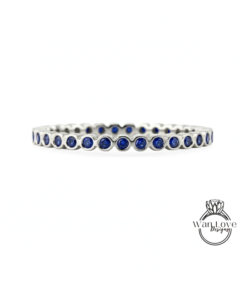 A silver bangle bracelet with blue gemstones, featuring a row of blue gemstones arranged in a circular pattern.