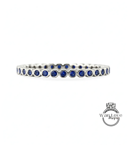 A silver bangle bracelet with blue gemstones, featuring a row of blue gemstones arranged in a circular pattern.