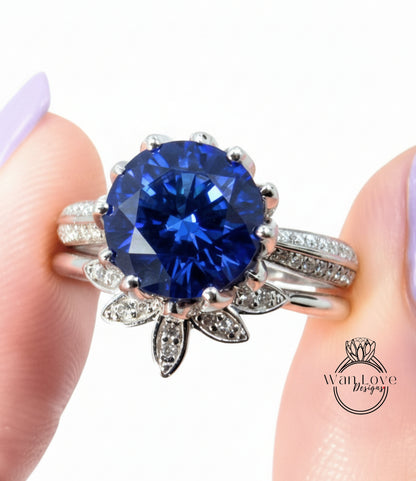 A close-up of a person's hand wearing a silver ring with a large blue gemstone, possibly a sapphire or blue topaz.
