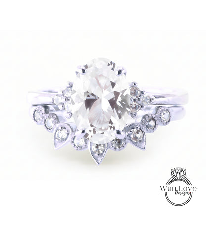 A close-up view of a diamond engagement ring with a large oval-shaped diamond at the center, surrounded by smaller diamonds and a floral-designed band.