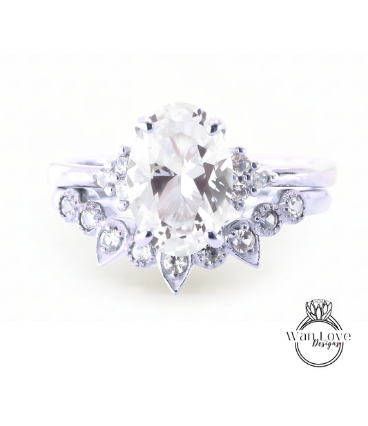 A close-up view of a diamond engagement ring with a large oval-shaped diamond at the center, surrounded by smaller diamonds and a floral-designed band.