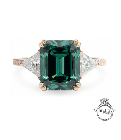 A large, green gemstone engagement ring with a gold band and three smaller diamonds on either side.