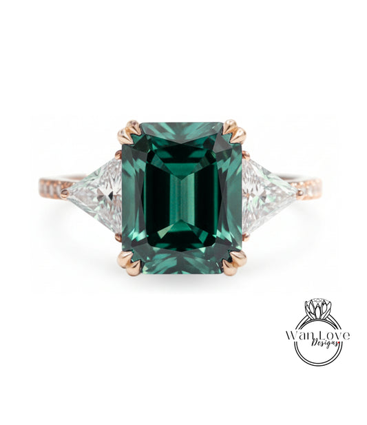 A large, green gemstone engagement ring with a gold band and three smaller diamonds on either side.