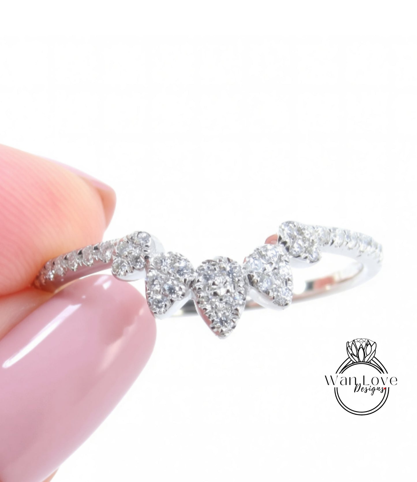 A close-up of a person's hand holding a ring with a cluster of diamonds on the band.