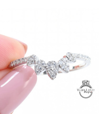 A close-up of a person's hand holding a ring with a cluster of diamonds on the band.