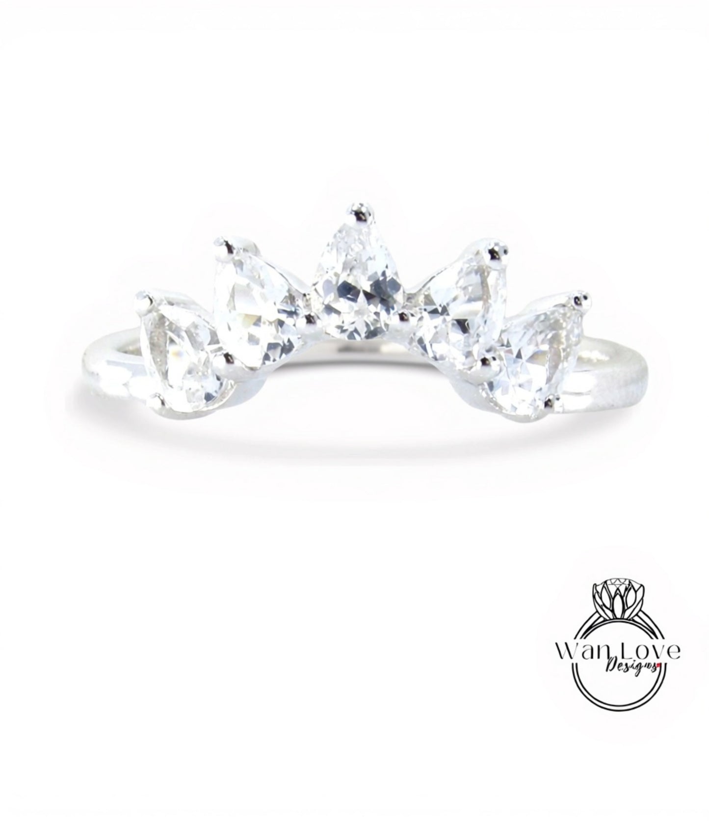 A silver ring with a row of clear gemstones, including pear-shaped and round-shaped stones, set in a band.