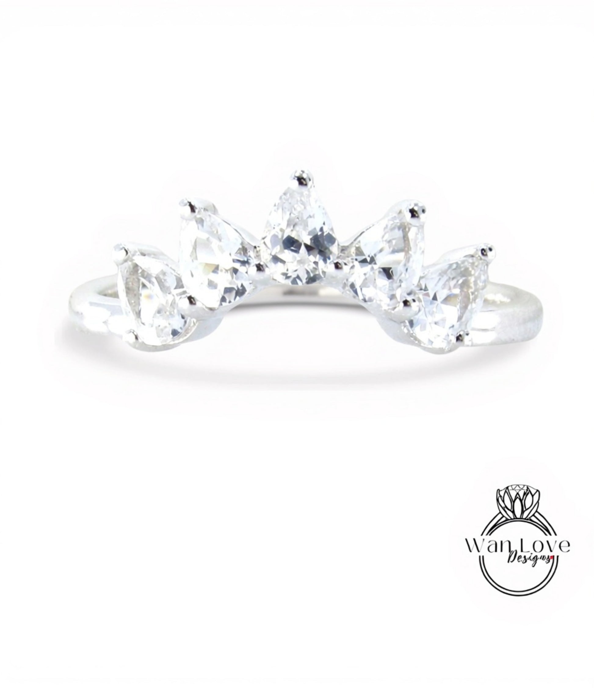 A silver ring with a row of clear gemstones, including pear-shaped and round-shaped stones, set in a band.