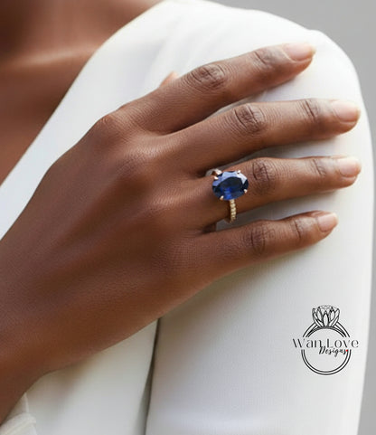 A close-up of a person's hand wearing a large blue gemstone ring on the ring finger.