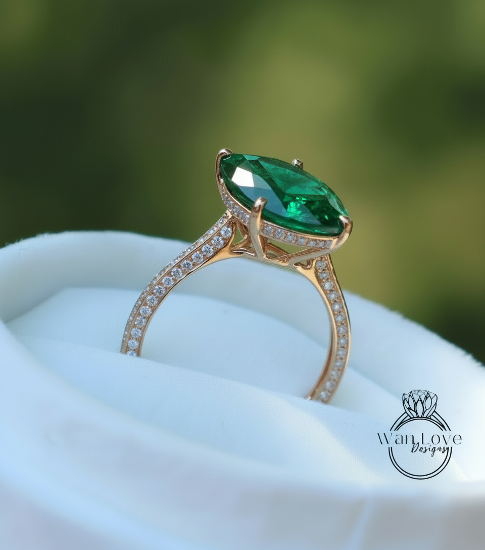 A gold ring with a large oval-shaped green gemstone, possibly an emerald, set in a diamond-encrusted band.
