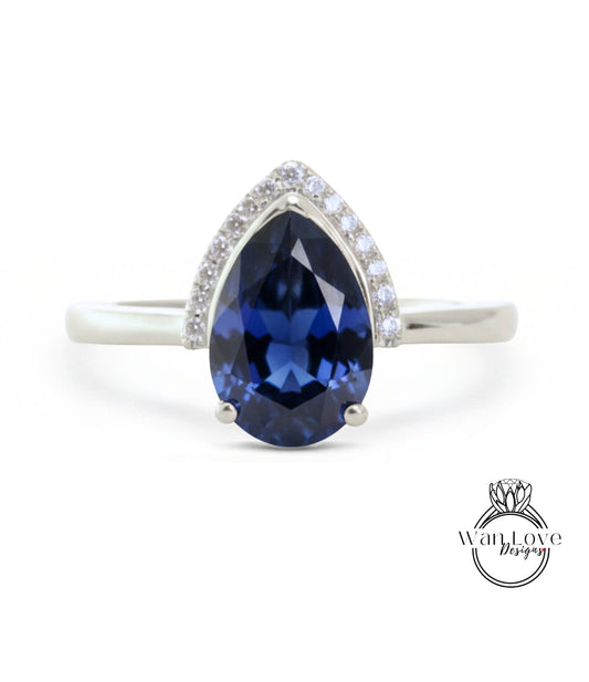 A silver ring with a large blue gemstone, likely a sapphire, as the centerpiece.