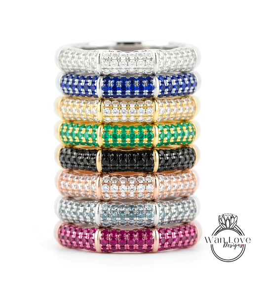 A stack of rings with colorful gemstone bands on top, showcasing various colors and patterns.