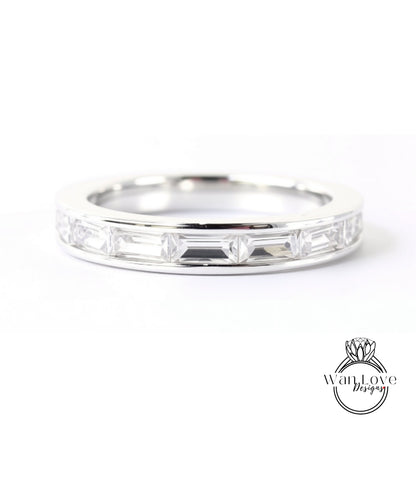 A silver ring with a row of clear gemstones, likely diamonds, set in a band.