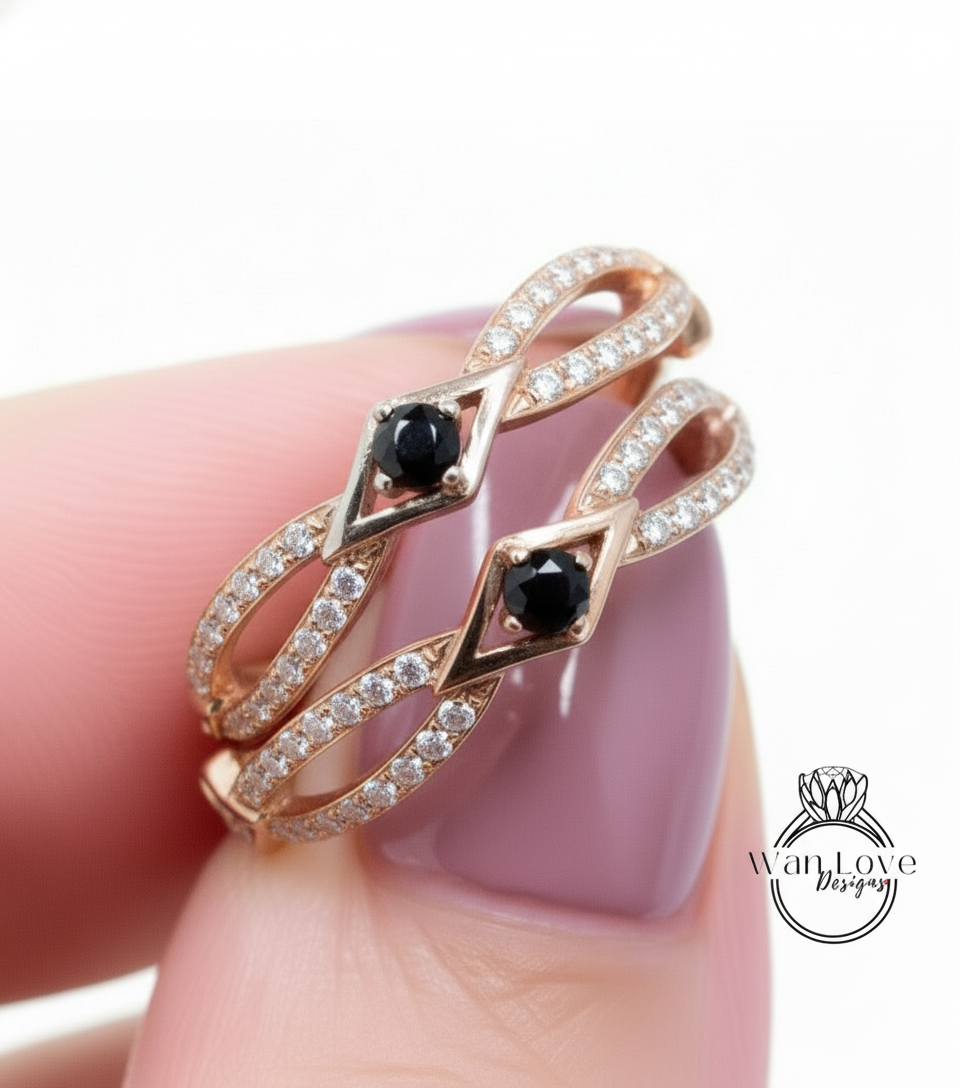 A close-up of a person's hand wearing a gold ring with two black gemstones.