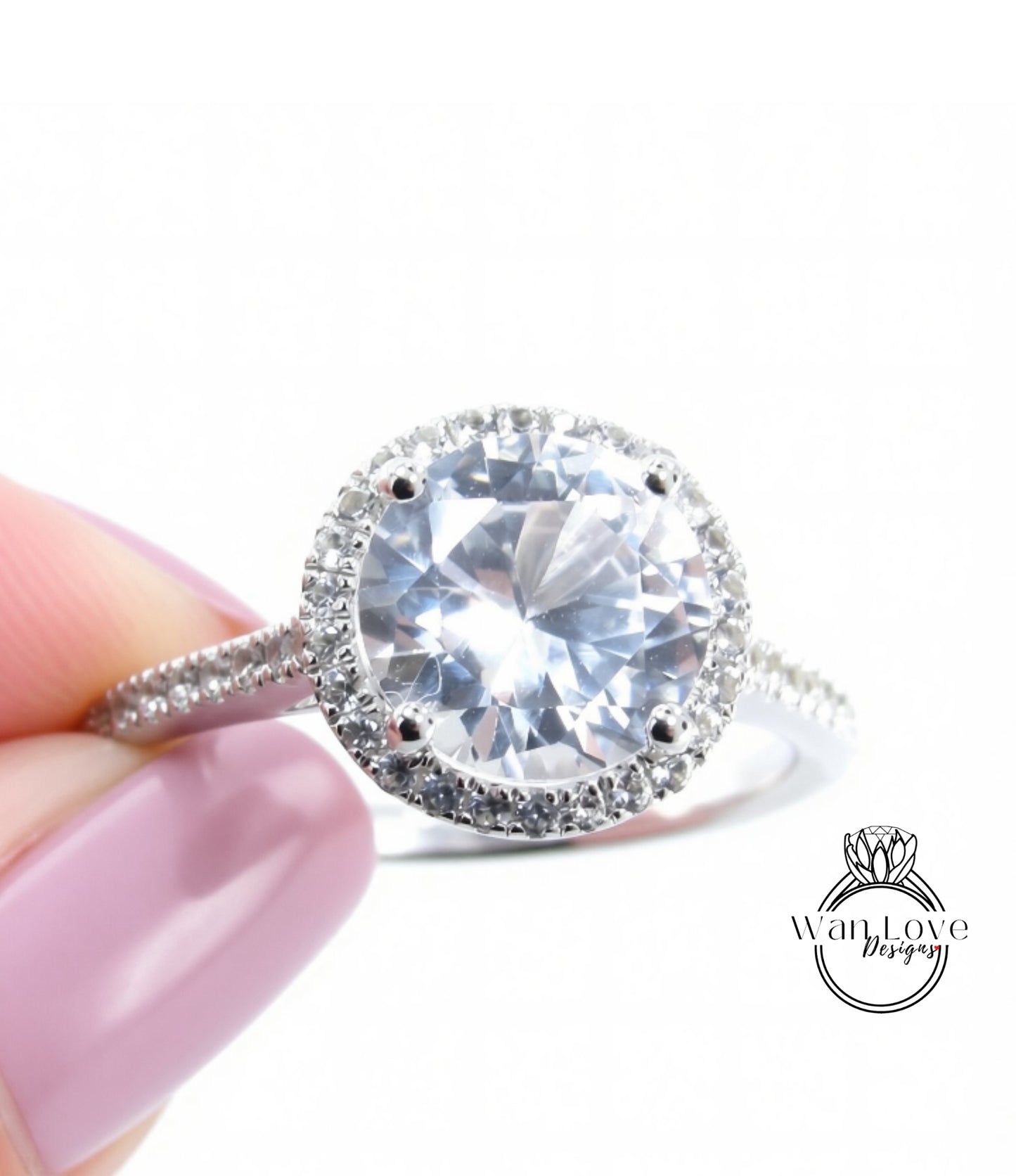A close-up of a diamond engagement ring being held by a person's hand, showcasing the large, clear gemstone surrounded by a halo of smaller diamonds.