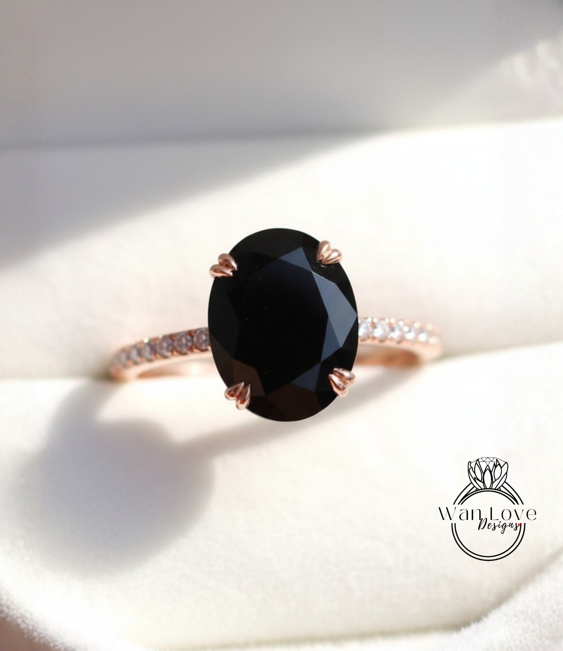 A close-up image of a rose gold ring with a large oval-shaped black gemstone, placed on a white background.