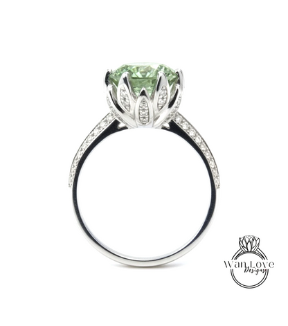 A silver ring with a large, green gemstone set in a decorative flower-like design.