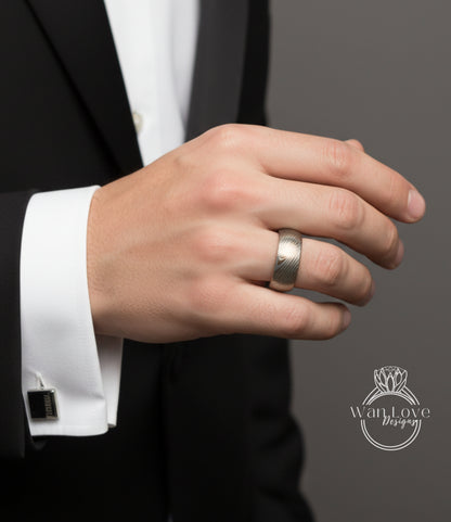 A close-up of a person's hand wearing a silver ring, with a black suit jacket visible.